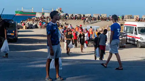 متطوعون من الصليب الأحمر يوزعون الطعام على مهاجرين، على شاطئ ترامبولين في سبتة، 22 أغسطس 2026.