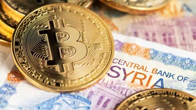 عملة بيتكوين فوق ورقة نقدية سورية تحمل توقيع "مصرف سوريا المركزي"، في رمزية  لتقاطع الانهيار النقدي مع صعود الأصول الرقمية.