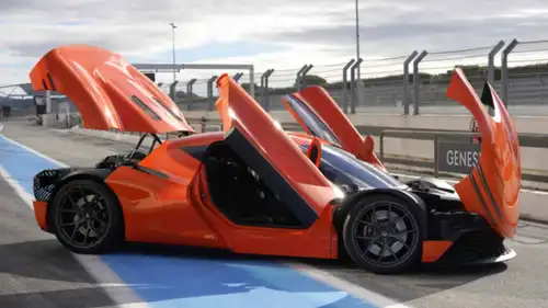 تظهر الصورة سيارة Genesis Magma GT التجريبية ذات اللون البرتقالي مع الأبواب المفتوحة للأعلى