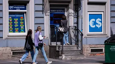 امرأة تدخل مكتباً لبيع وشراء العملات في سان بطرسبرغ، روسيا، يوم 14 يونيو 2024.