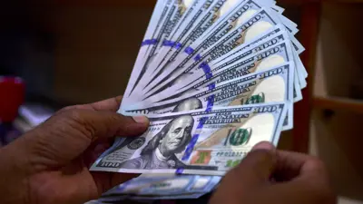 تاجر عملات أجنبية يعدُّ أوراقاً نقدية من الدولار الأميركي في سوق العملات بمدينة كراتشي الباكستانية، يوم 19 يوليو 2022.