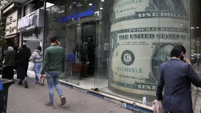 أشخاص يمرون بجوار مكتب صرافة في العاصمة المصرية القاهرة، في 21 مارس 2022.