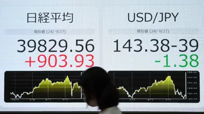 تمر أمام شاشة إلكترونية تظهر مستوى إغلاق مؤشر «نيكاي 225» للأسهم اليابانية، وسعر صرف الدولار الأميركي مقابل الين الياباني، في أحد شوارع طوكيو يوم 27 سبتمبر 2024.