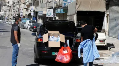 عمال الرعاية الصحية الأردنيون يتخلصون من معدات الحماية بعد أخذ عينات مسحة لفيروس كورونا في أحد أحياء عمان - 16 أكتوبر2020