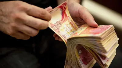 عملات ورقية من الدينار العراقي بيد أحد الصرافين في مدينة البصرة، جنوب العراق، يوم 12 ديسمبر 2023.