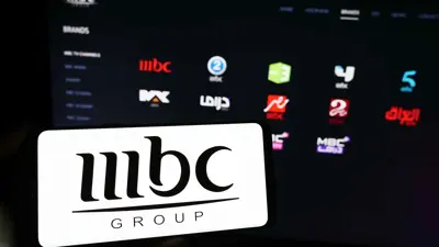 شعار «إم بي سي» على شاشة هاتف ذكي فيما تظهر في الخلفية شاشة حاسوب تعرض موقع الشركة الإلكتروني، يوم 9 نوفمبر 2023.