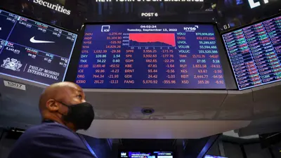 متداول يقف تحت شاشة على أرضية بورصة وول ستريت في مانهاتن الأميركية في 13 سبتمبر 2022