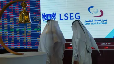 متداولان يتابعان شاشات البورصة القطرية في العاصمة الدوحة يوم 20 يونيو 2023.